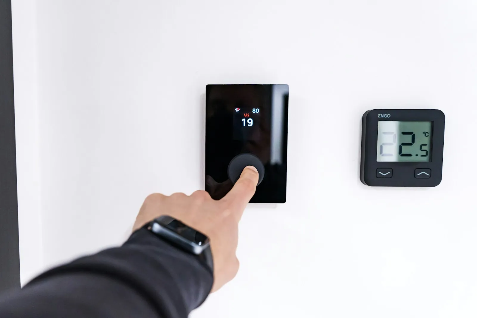 Adjusting a digital thermostat on a wall